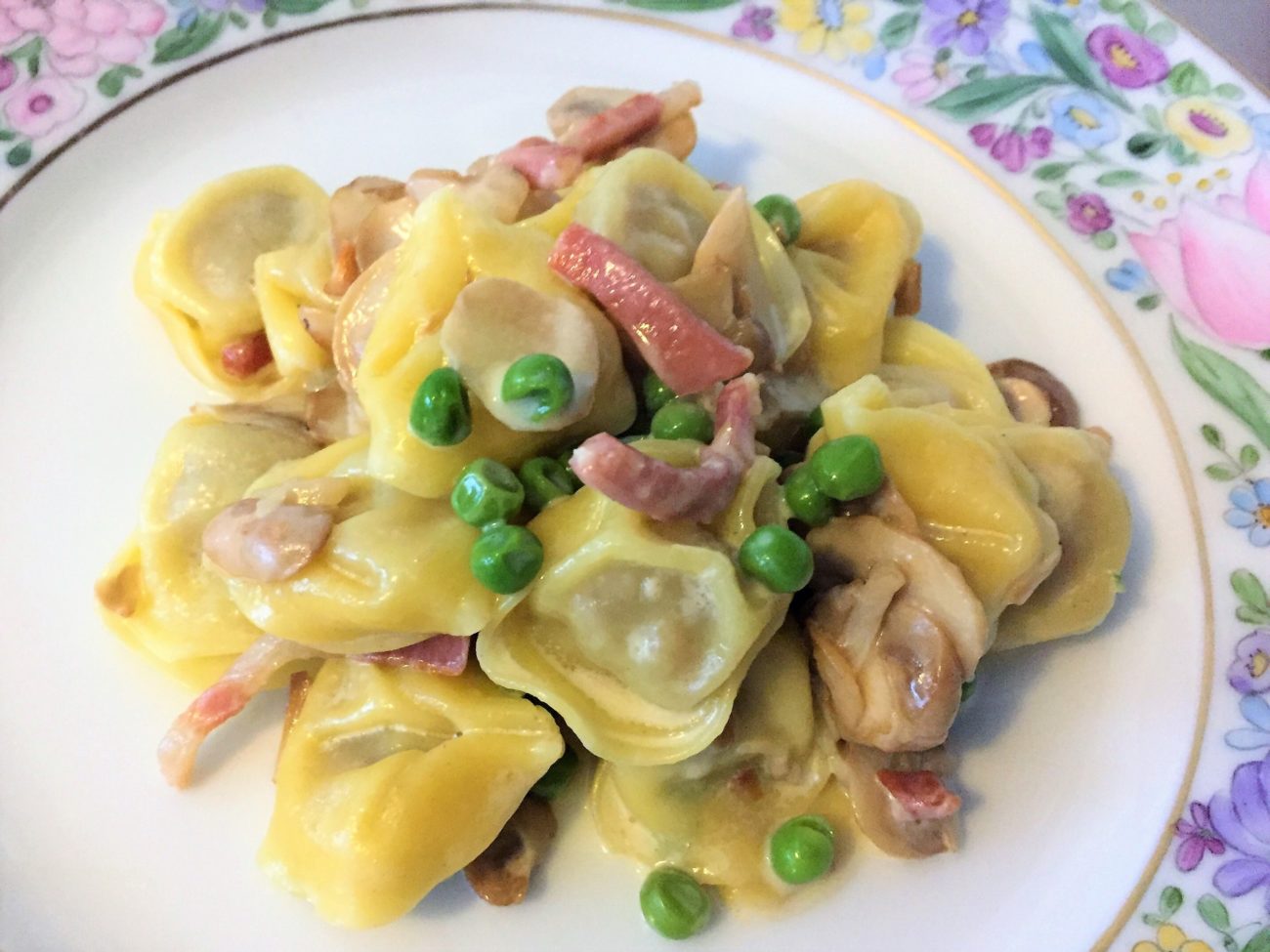 Tortelloni con champignon, piselli e pancetta affumicata