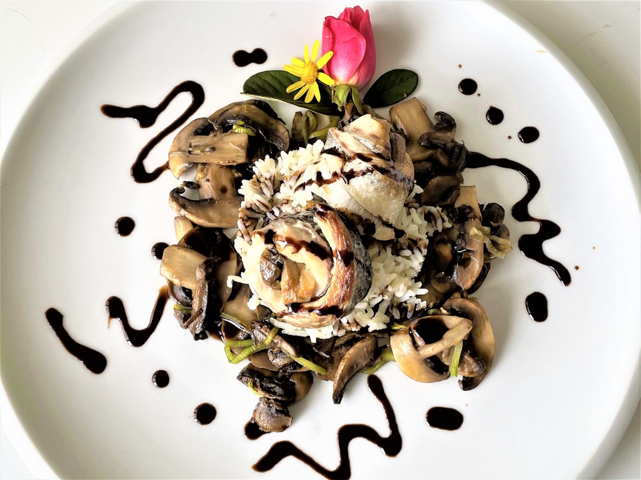Rotolini di branzino con letto di champignon con salsa all’aceto balsamico